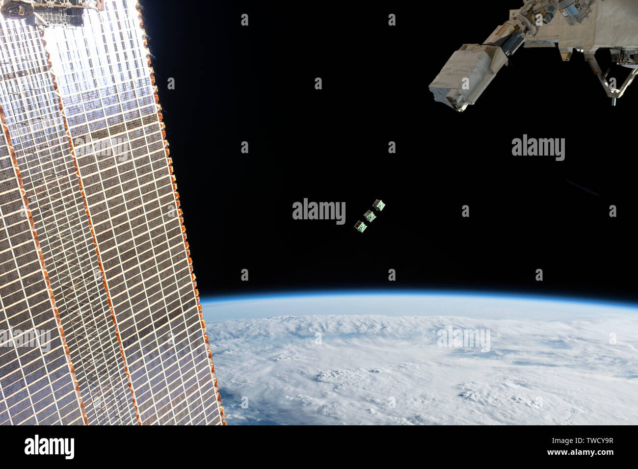 A set of tiny satellite sfrom Singapore, also known as a CubeSat, is ejected from the Japanese Small Satellite Orbital Deployer past the solar array of the International Space Station June 17, 2019 in Earth Orbit. Stock Photo