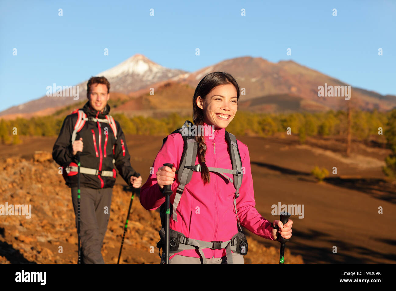People hiking - healthy active lifestyle couple. Hikers walking in beautiful mountain nature landscape. Woman and man hikers walking during hike on volcano Teide, Tenerife, Canary Islands, Spain. Stock Photo