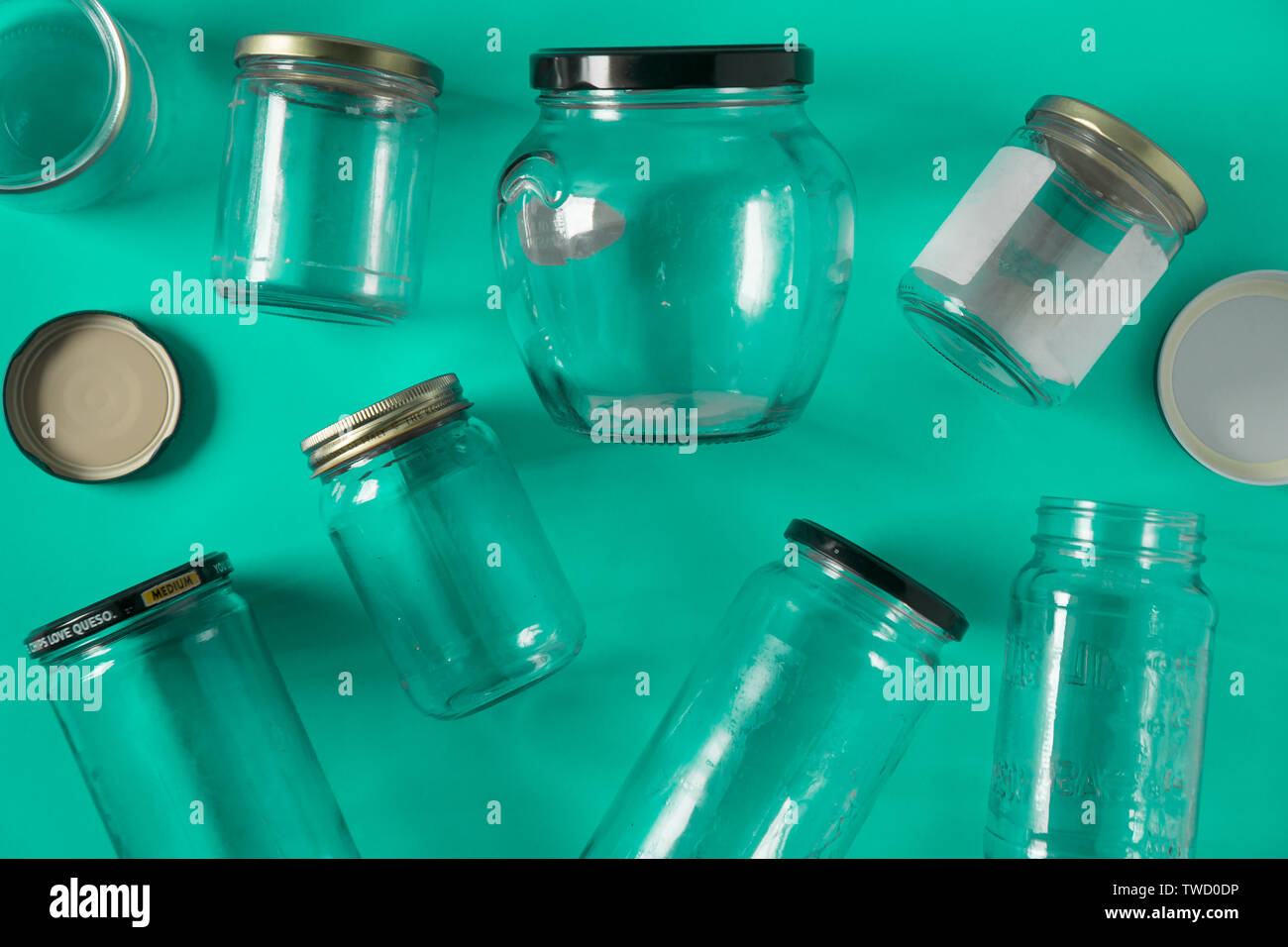 Transparent glass jars with lids isolated on teal green background, top