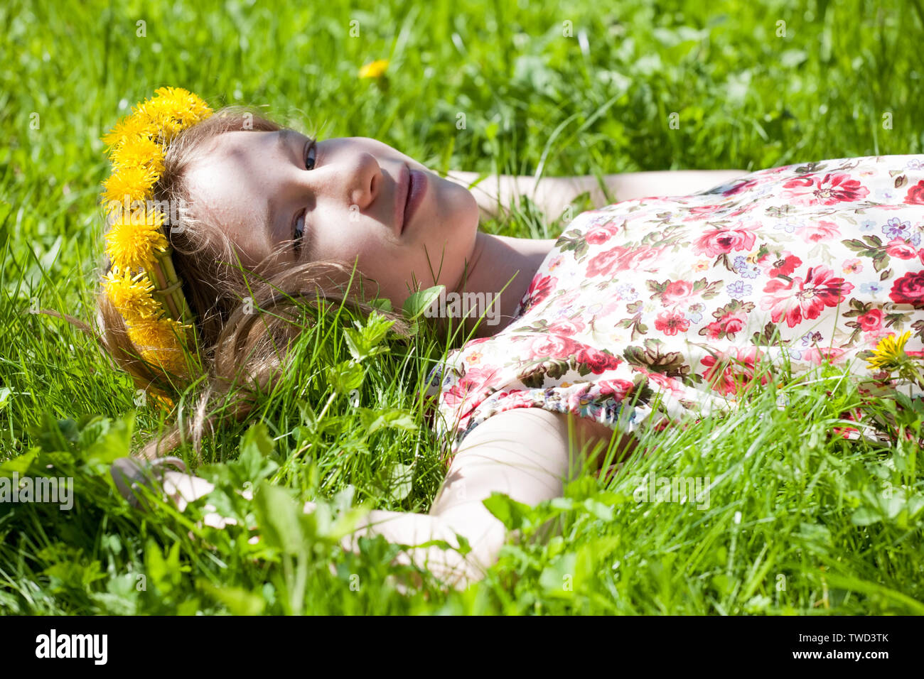 young girl in wreath of dandelions laying on green grass meadow Stock ...