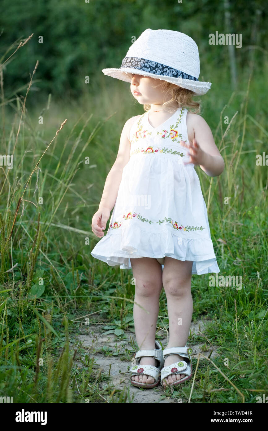 toddler girl in beautiful white dress and funny big hat Stock Photo