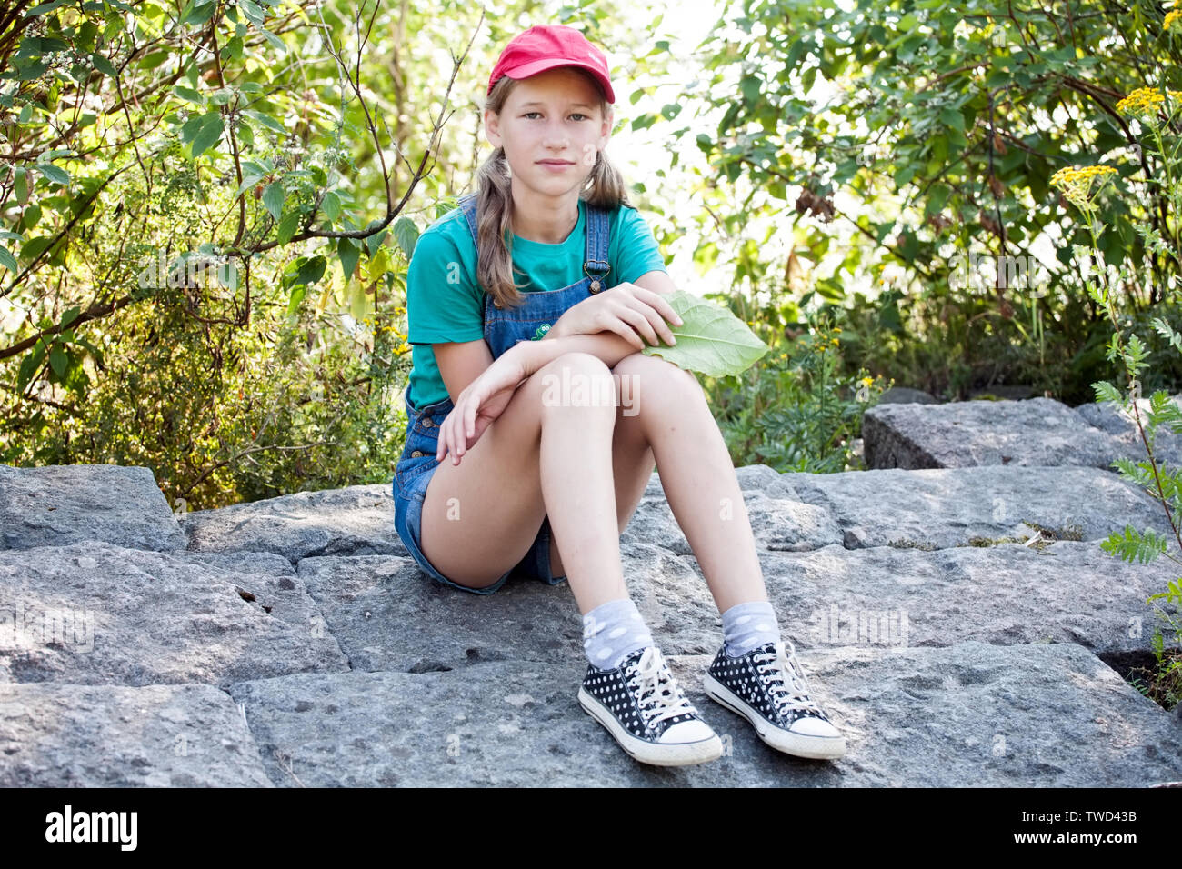 teenager caucasian girl sitting on stone pavement Stock Photo