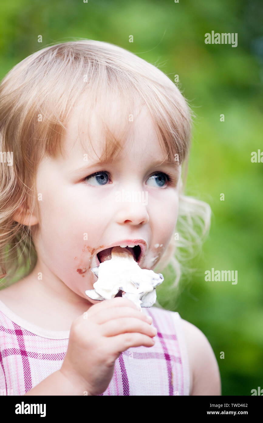 little girl eating ice cream on summer outdoor background Stock Photo