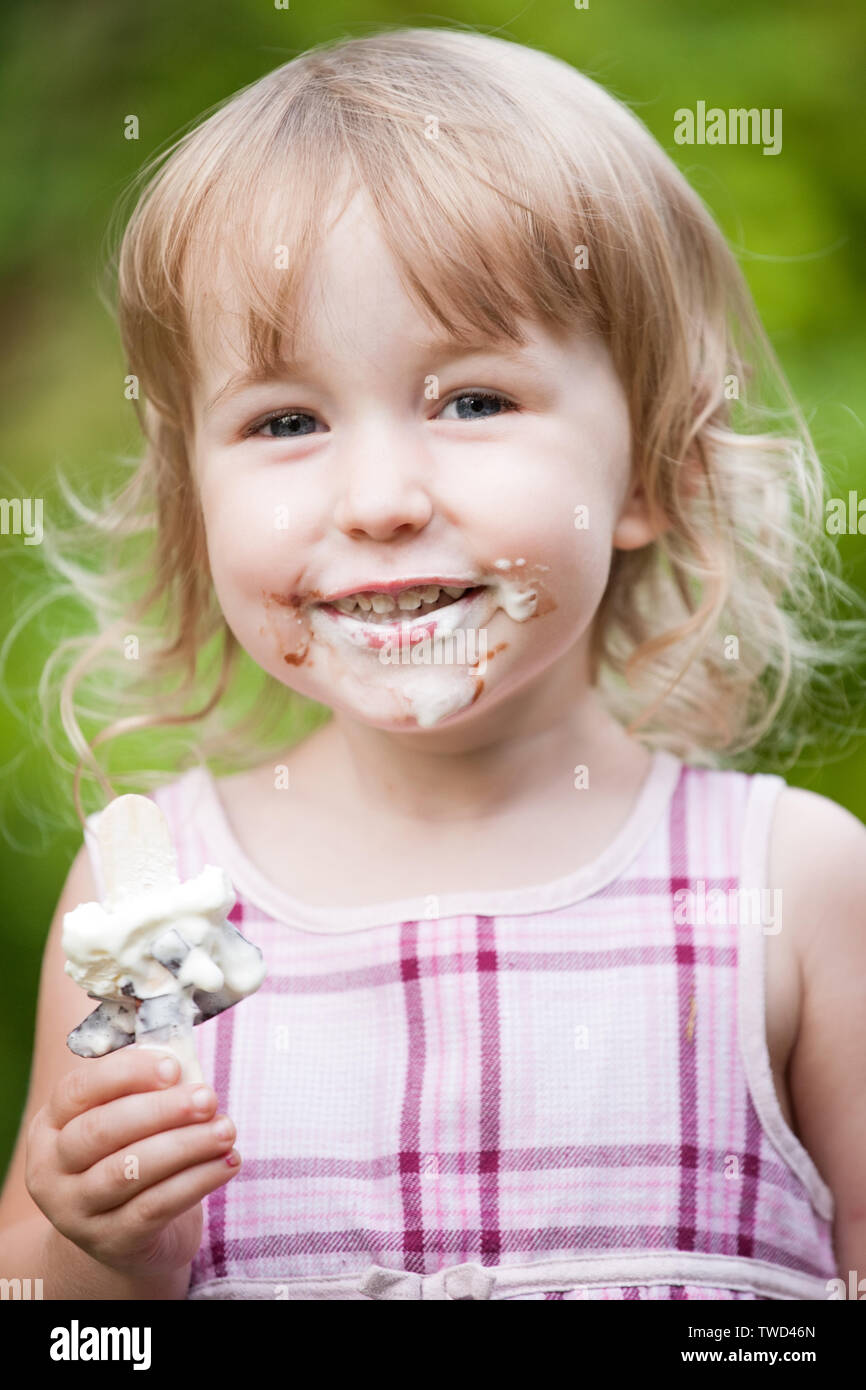 smiling little girl with soiled face and ice cream in the hand closeup view Stock Photo