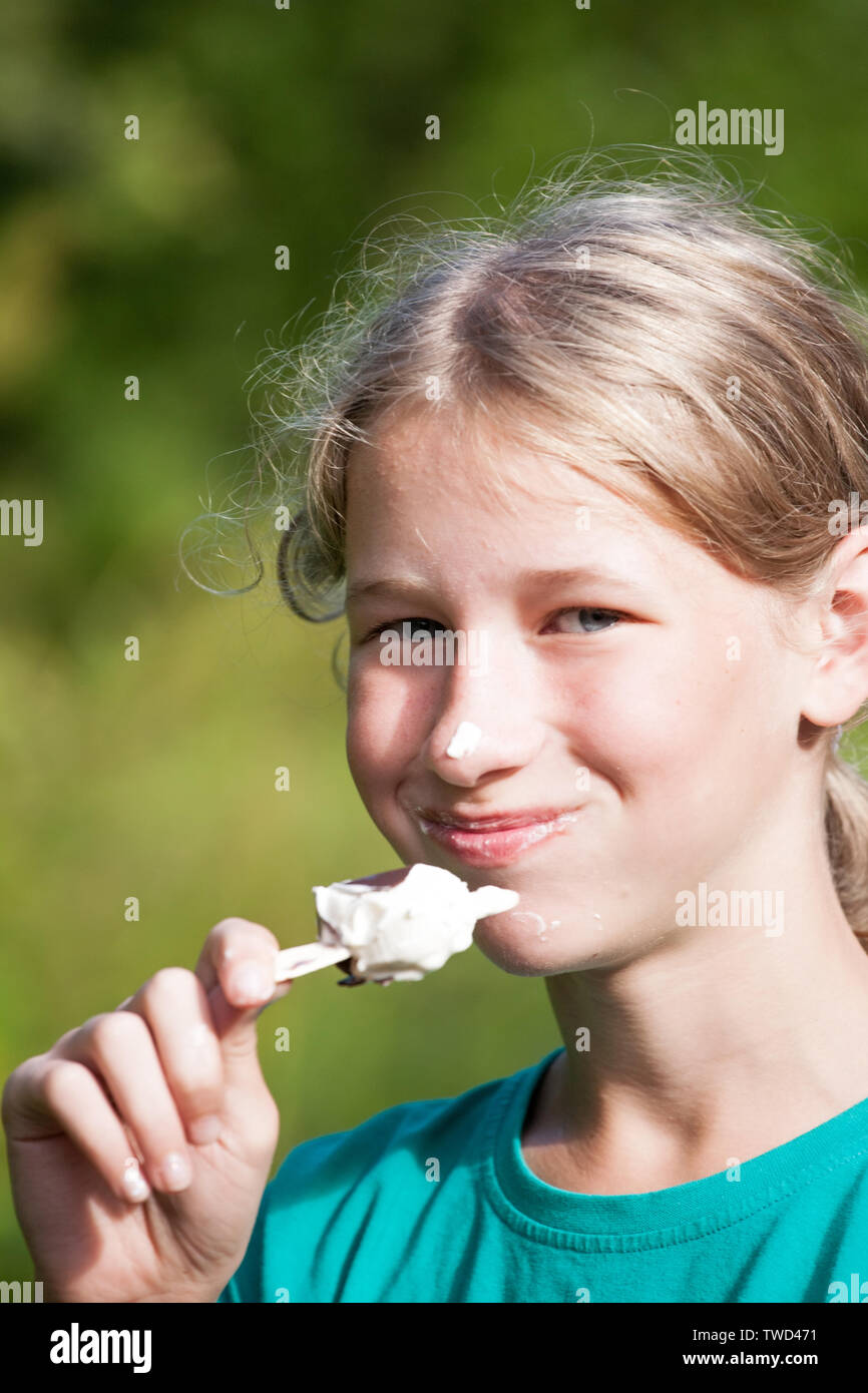 young girl eating ice cream on summer outdoor background Stock Photo