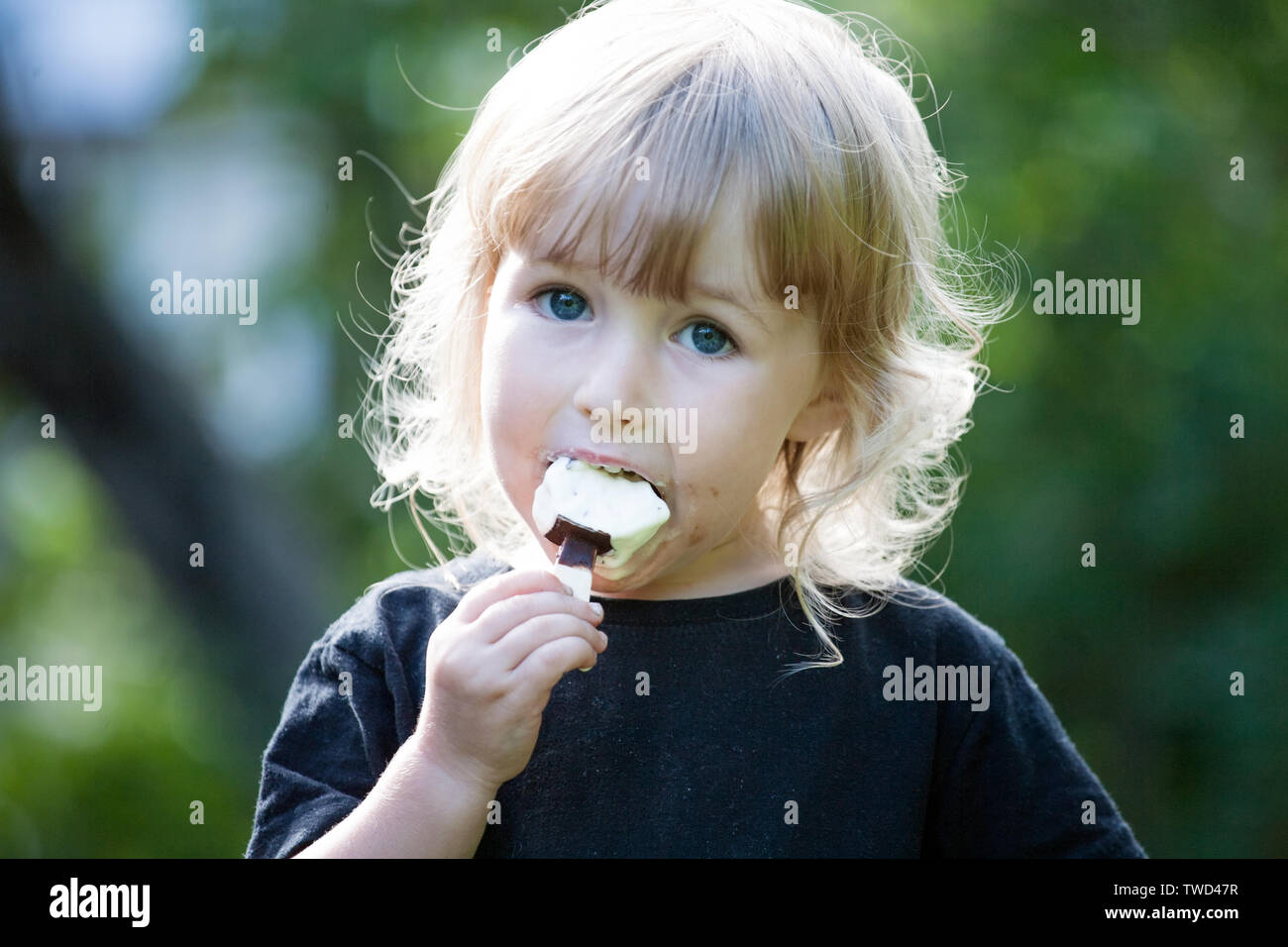 little girl with chocolate popsicle ice cream in the hand closeup view Stock Photo