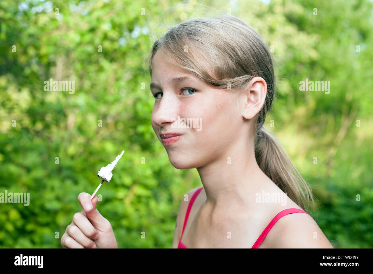 smiling teen girl with chocolate popsicle ice cream in the hand on green outdoor background closeup view Stock Photo