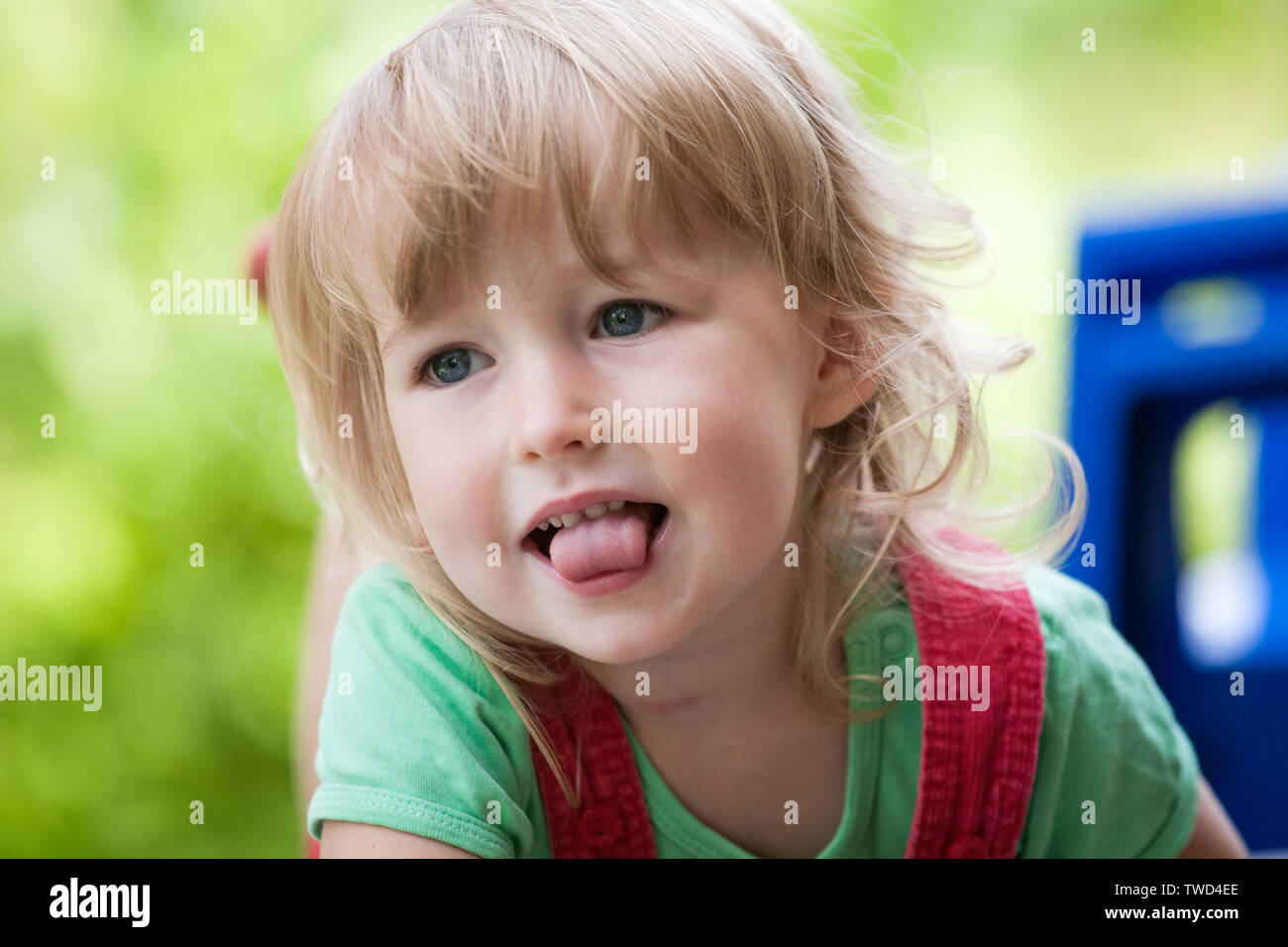 little child caucasian girl face closeup on green summer outdoor background Stock Photo