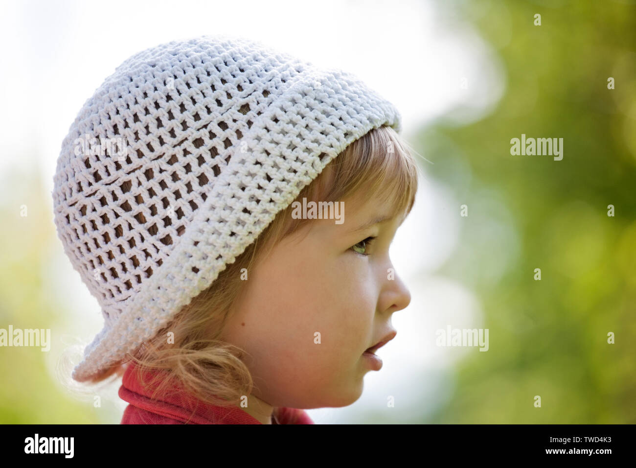little kid pretty caucasian girl in white hat face side view closeup Stock Photo