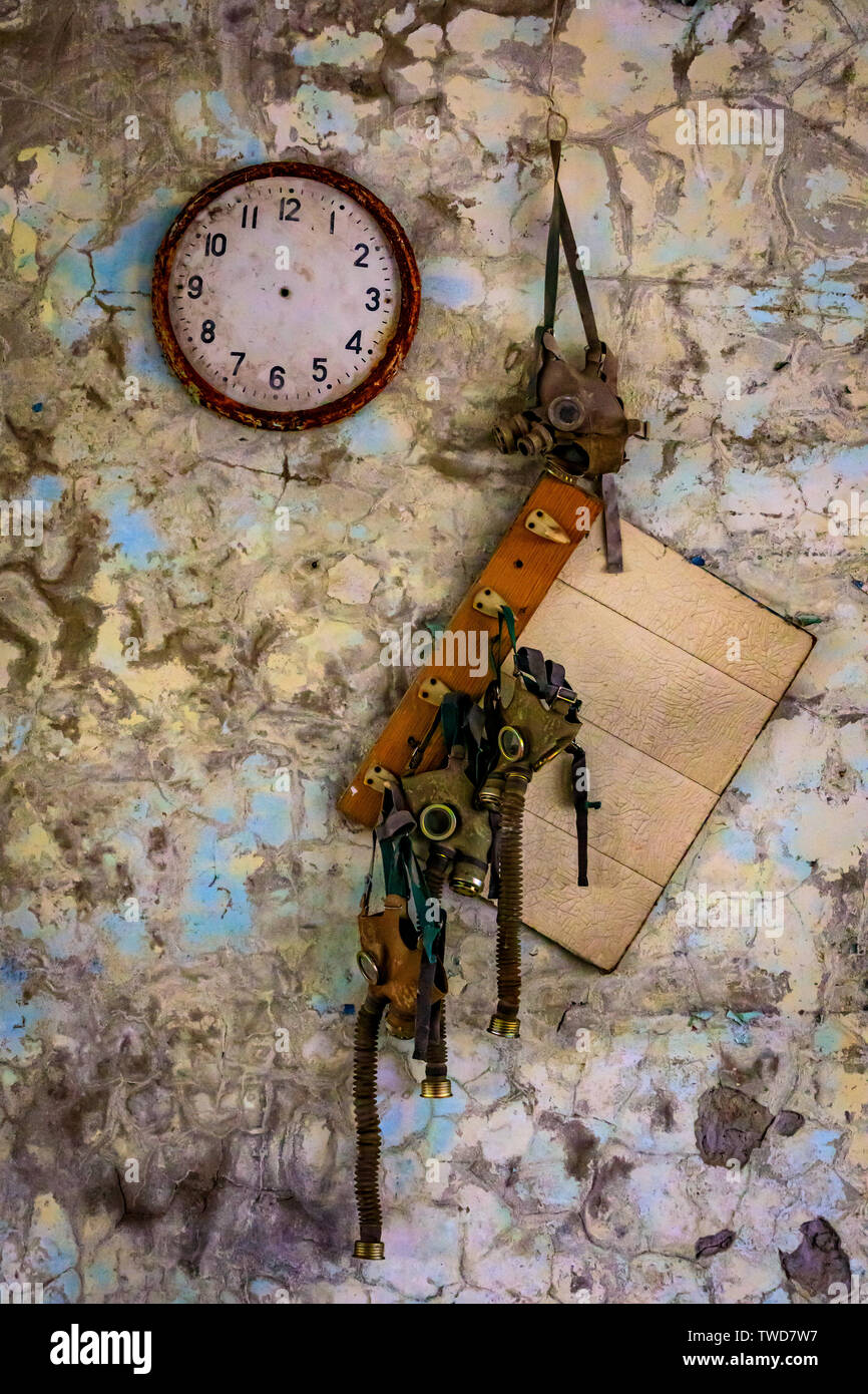 Eastern Europe, Ukraine, Pripyat, Chernobyl. A clock with no hands, and gas masks hanging from hooks. Stock Photo