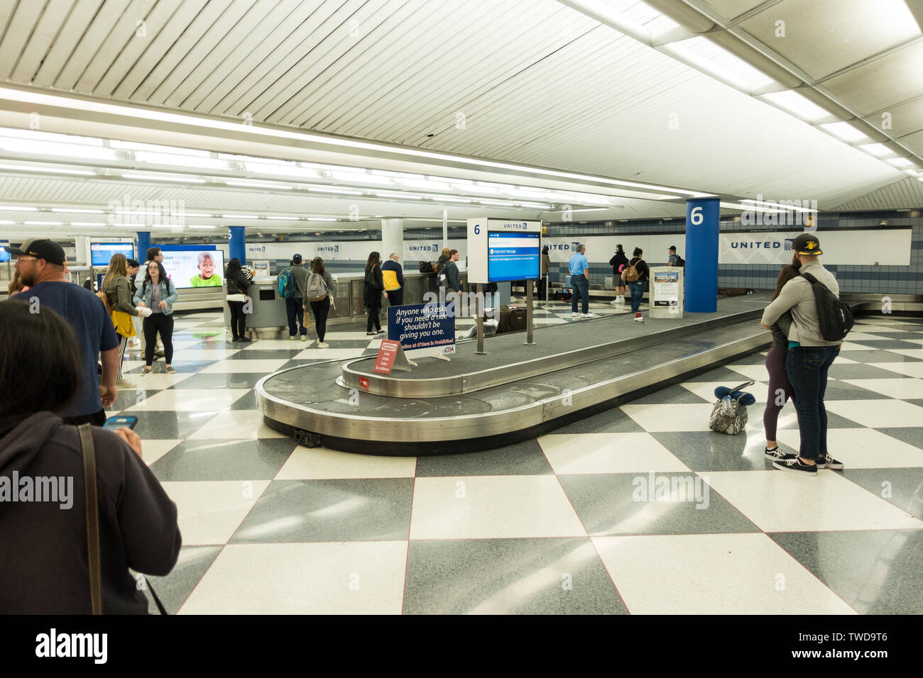 People awaiting at the luggage carousel / conveyor belt at the baggage