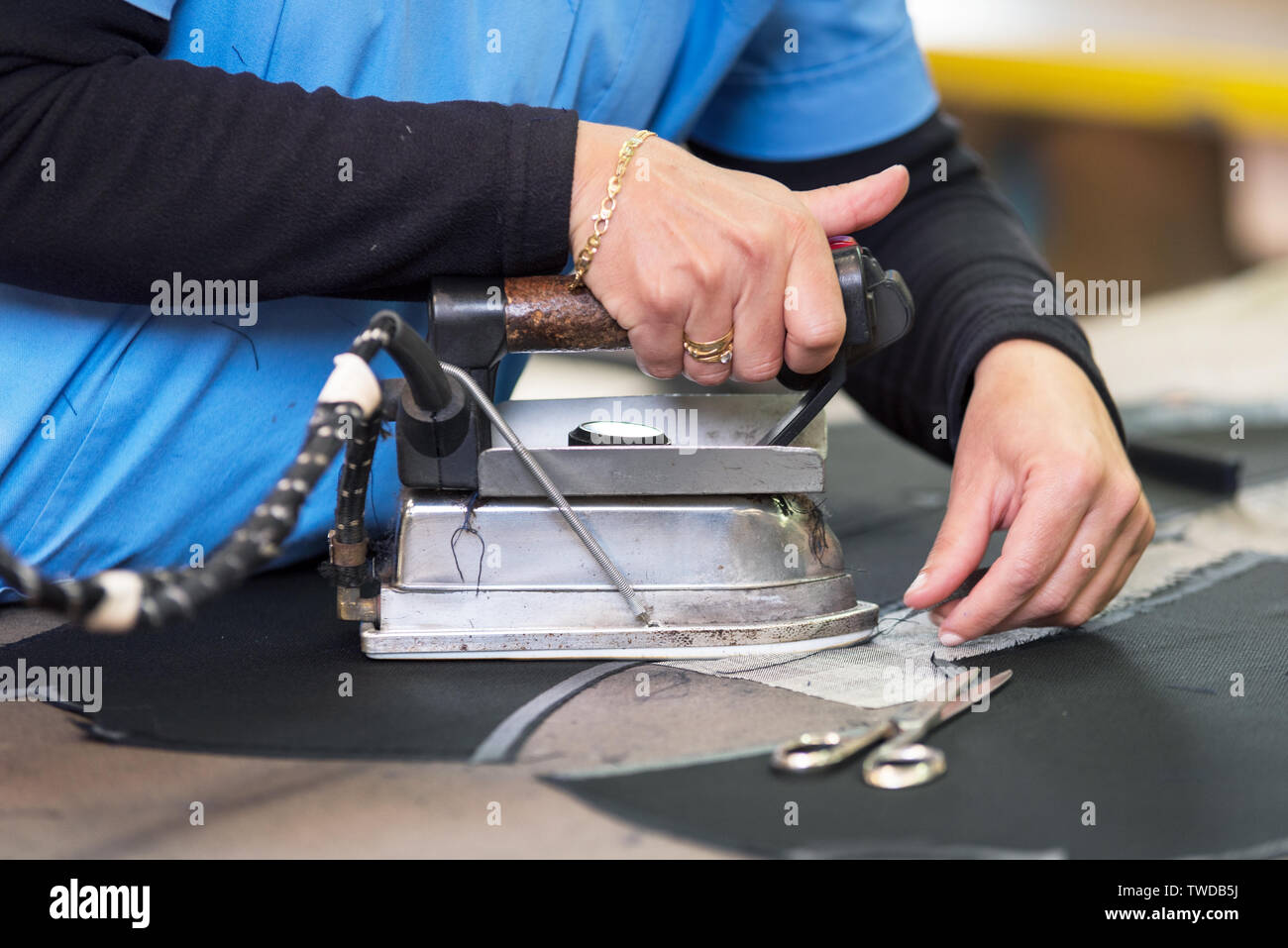 Semstress ironing the fabric. seamstress irons fabirc in a sewing workshop . Stock Photo