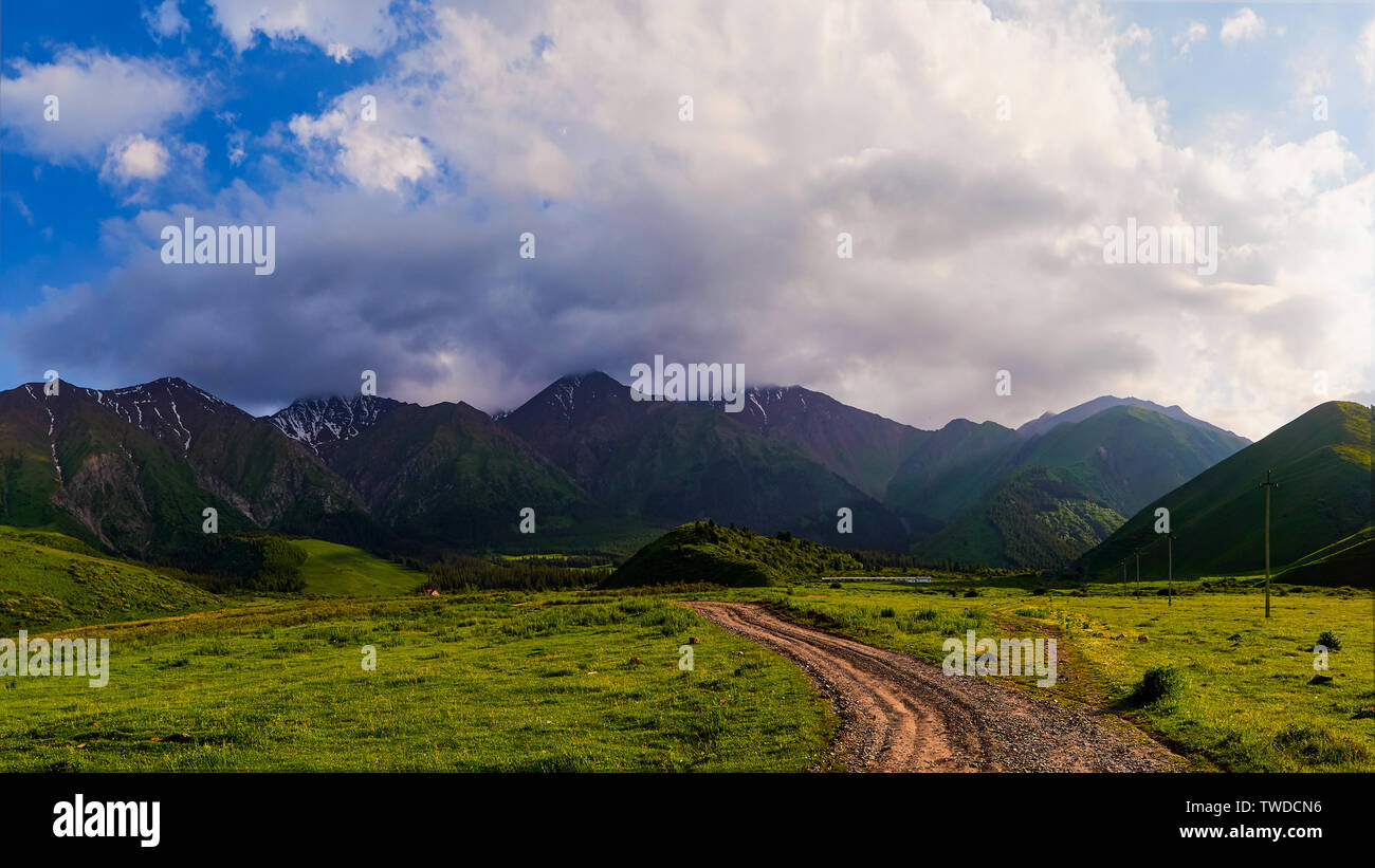 Panorama of a mountain valley in the summer. Fabulous sunset in the mountains, amazing nature, a mountain range. The road leads to the depths of the m Stock Photo
