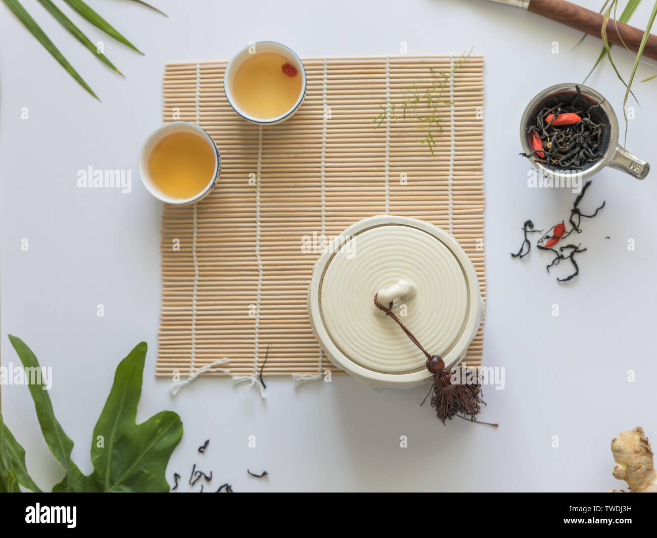 On the bamboo curtain is a white teahouse and two cups of tea. Stock Photo