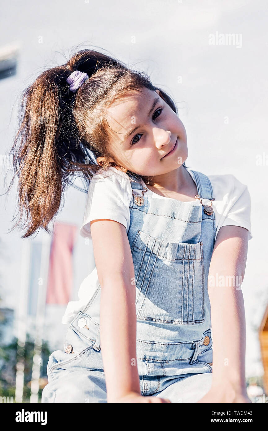 Cute happy caucasian girl in denim overalls smiling. Lifestyle Stock Photo  - Alamy