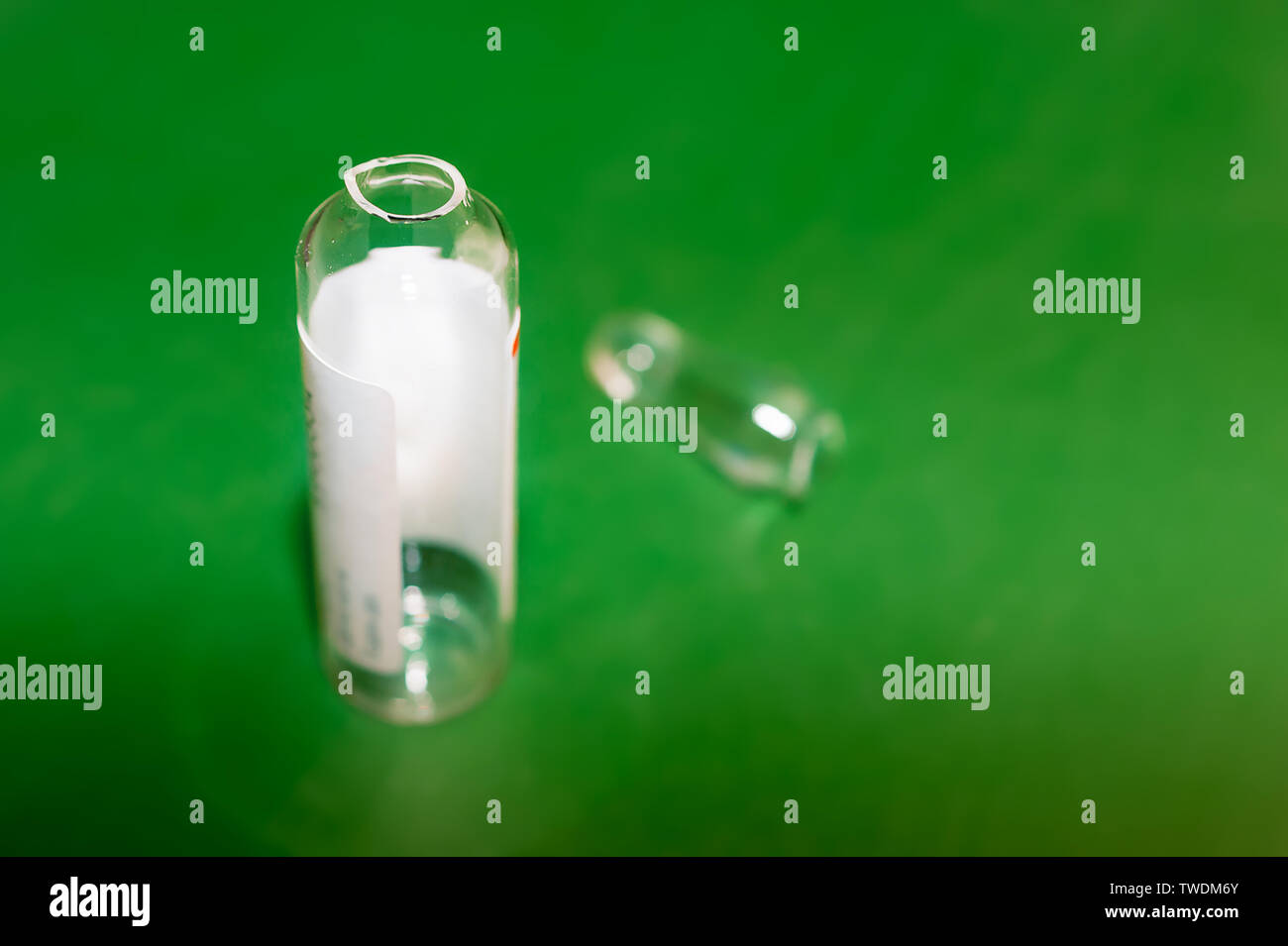 Empty Opened Glass Ampoule with White Label and Its Head, or Conical Tip on Green Background