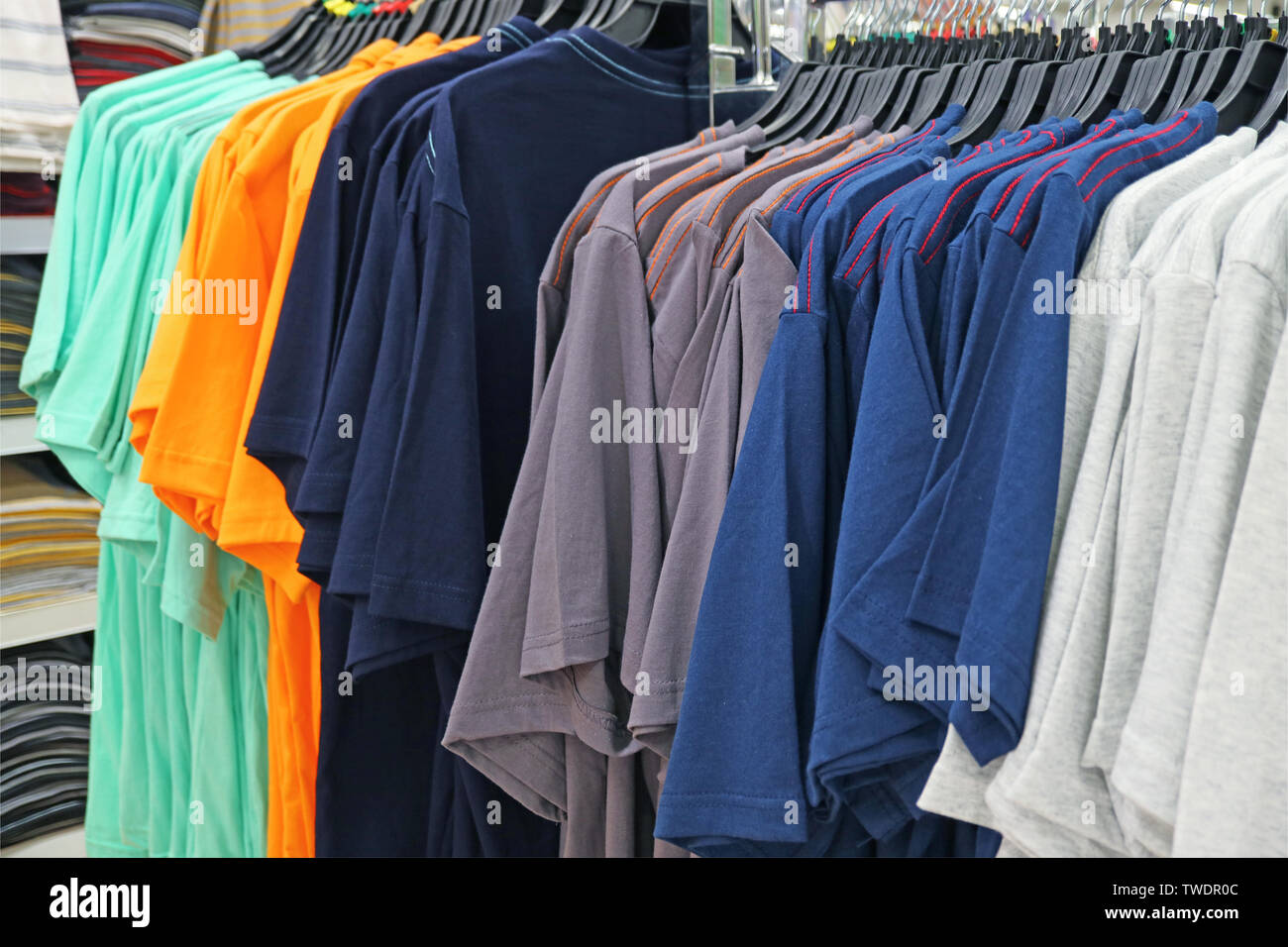 Row of Multi-color Men's T-shirts on Cloth Hangers in the Store Stock Photo