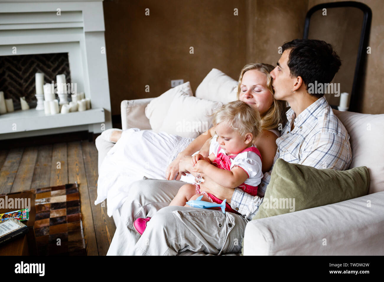Tender family hugs. Mom, dad and daughter enjoy each other at home on ...