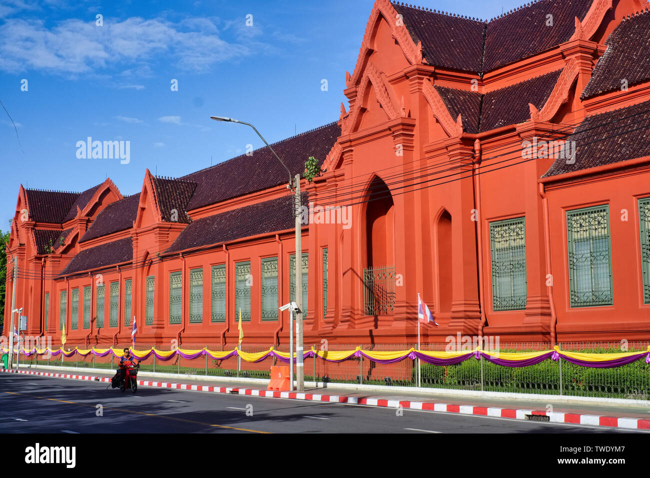 A motorcyclist passes the Thawornwatthu Building or Tuek Daeng, a former library for monks in Bangkok, Thailand Stock Photo