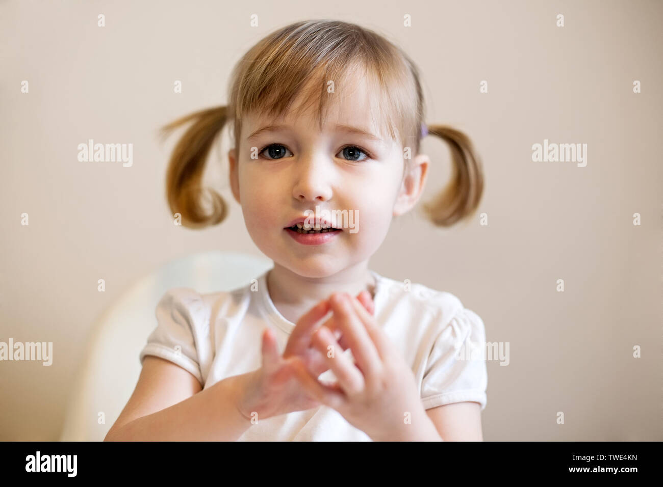 little amazed kid Caucasian girl with wide-open eyes cute closeup portrait on plain background Stock Photo