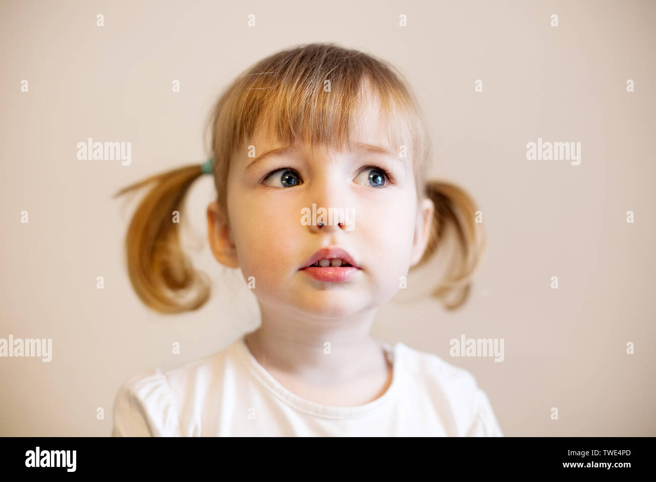 cute child girl with two pigtails and quiff of blonde hair closeup portrait Stock Photo