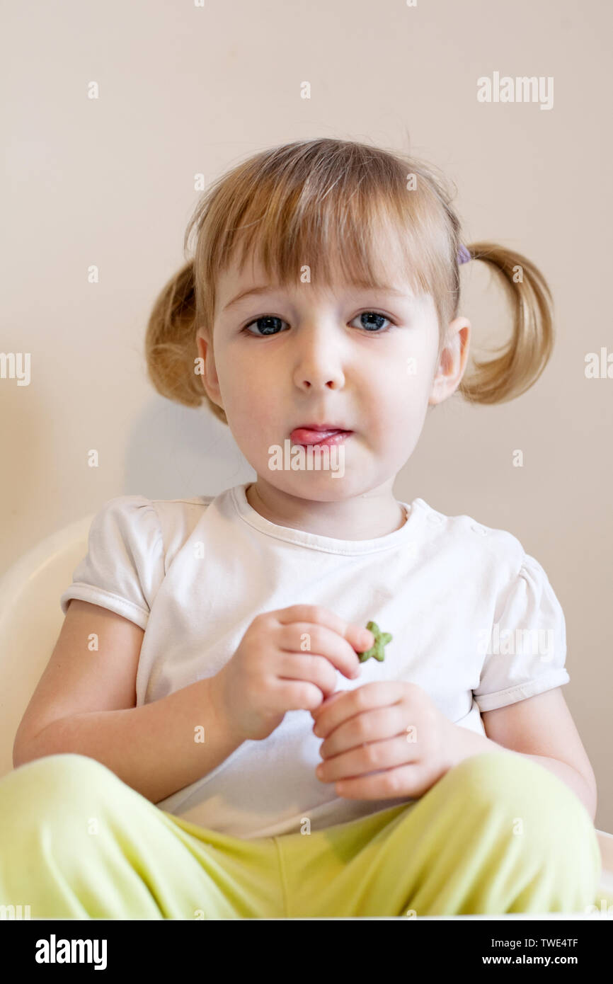 closeup face portrait of funny two years old blonde white girl on wall backgroundcloseup face portrait of funny two years old blonde white girl on stu Stock Photo