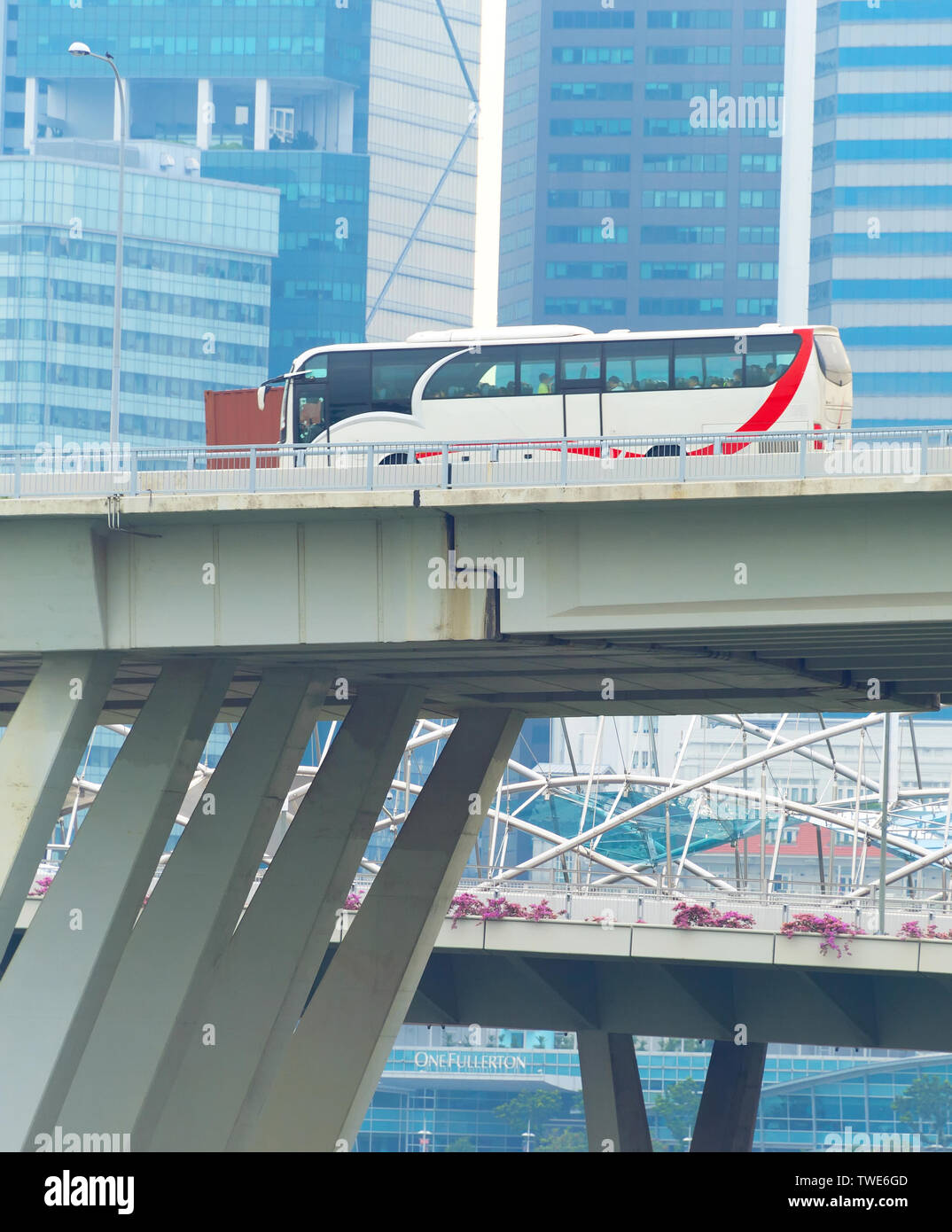 Bus driving by bridge of modern construction, Singapore skyscrapers in ...