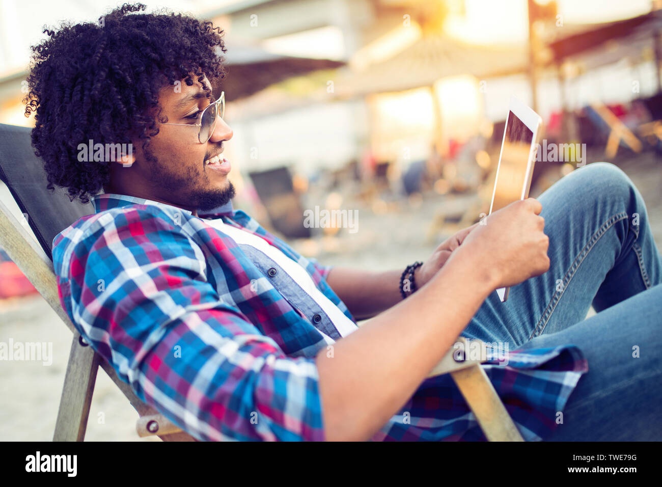 Banking online, portrait of happy black business man with tablet on the beach Stock Photo