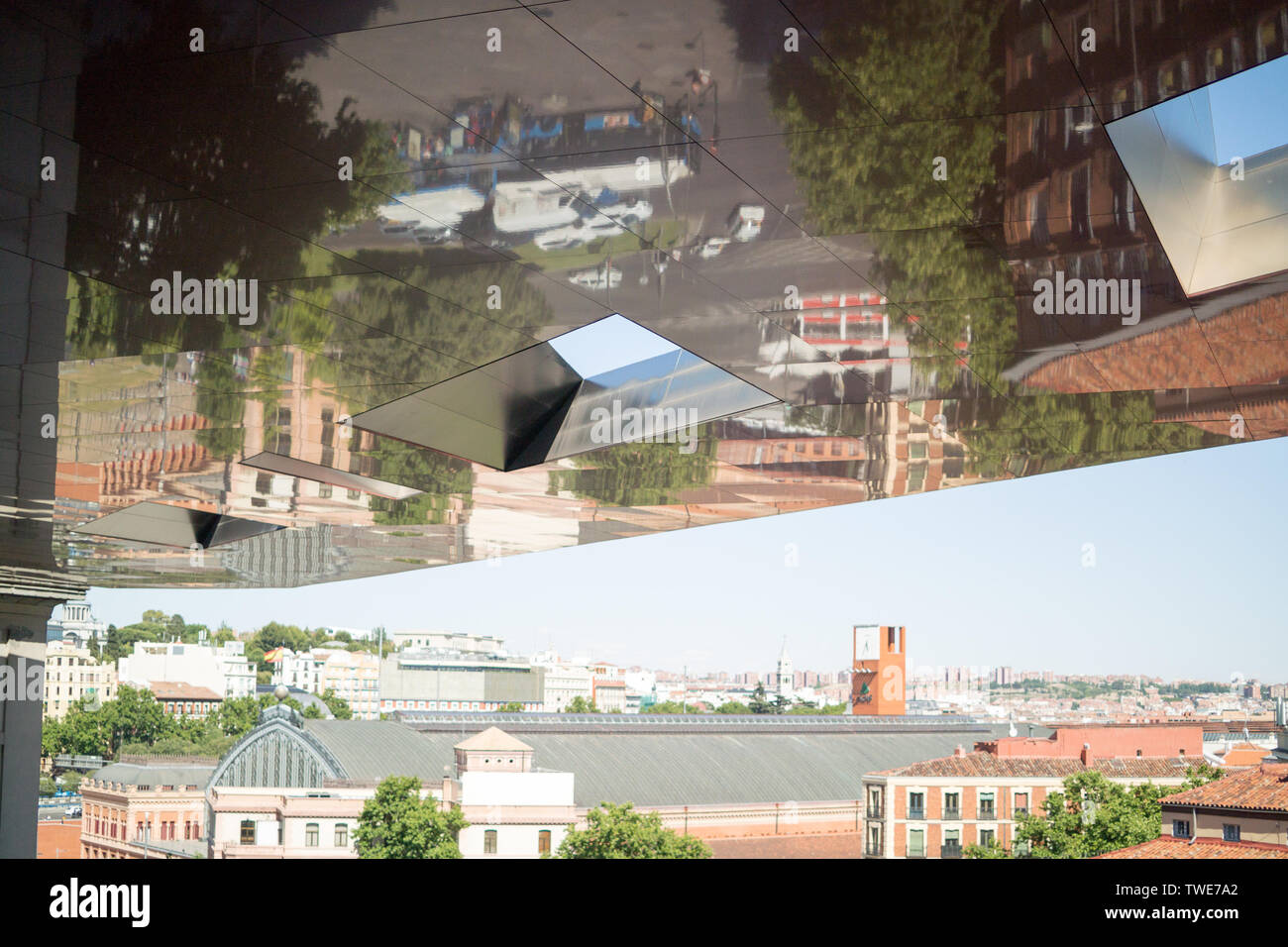Madrid street scene reflected in the overhanging roof of the Museo Nacional Centro de Arte and view towards Madrid-Puerta de Atocha station. Stock Photo