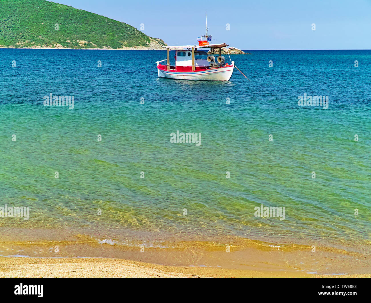Beautiful sandy beach with crystal clear water and boat in Nea Peramos, Greece. Stock Photo