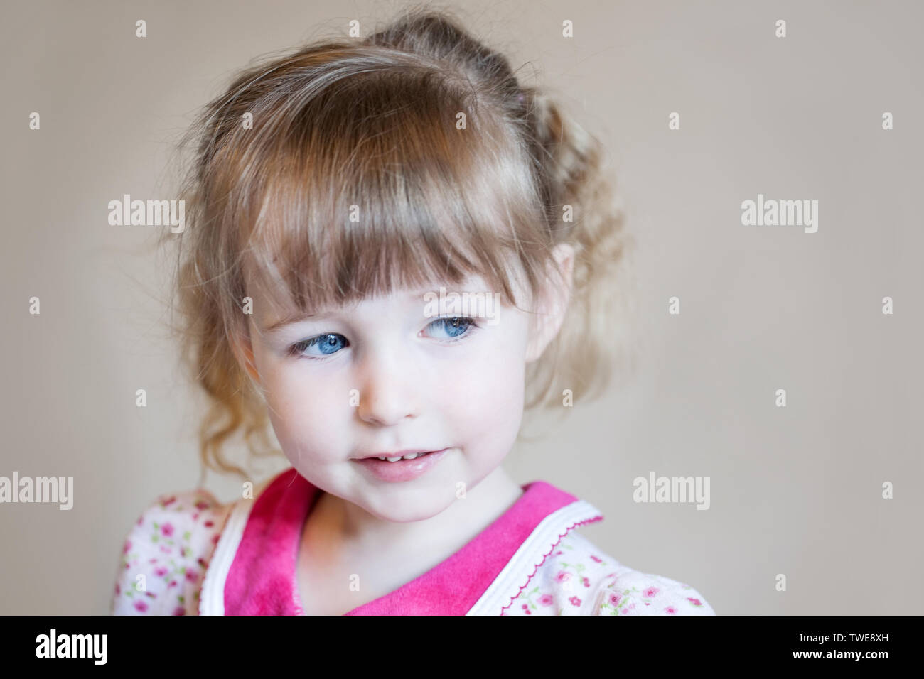 beautiful white child girl face closeup portrait on beige wall background Stock Photo