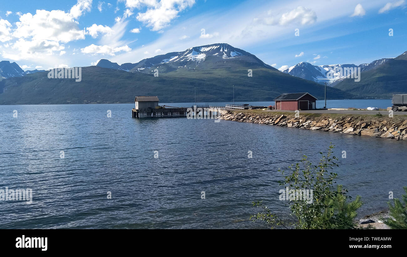 a pier with small house on blue water and mountains background Stock Photo