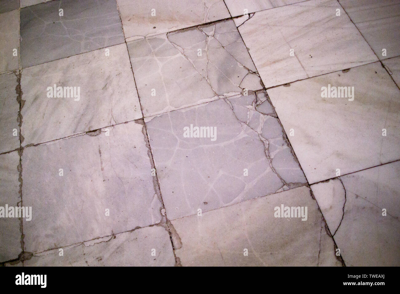 Aged and cracked square marble floor tiles laid in a grid pattern in former hospital building, finished in 1805 in Madrid, Spain Stock Photo