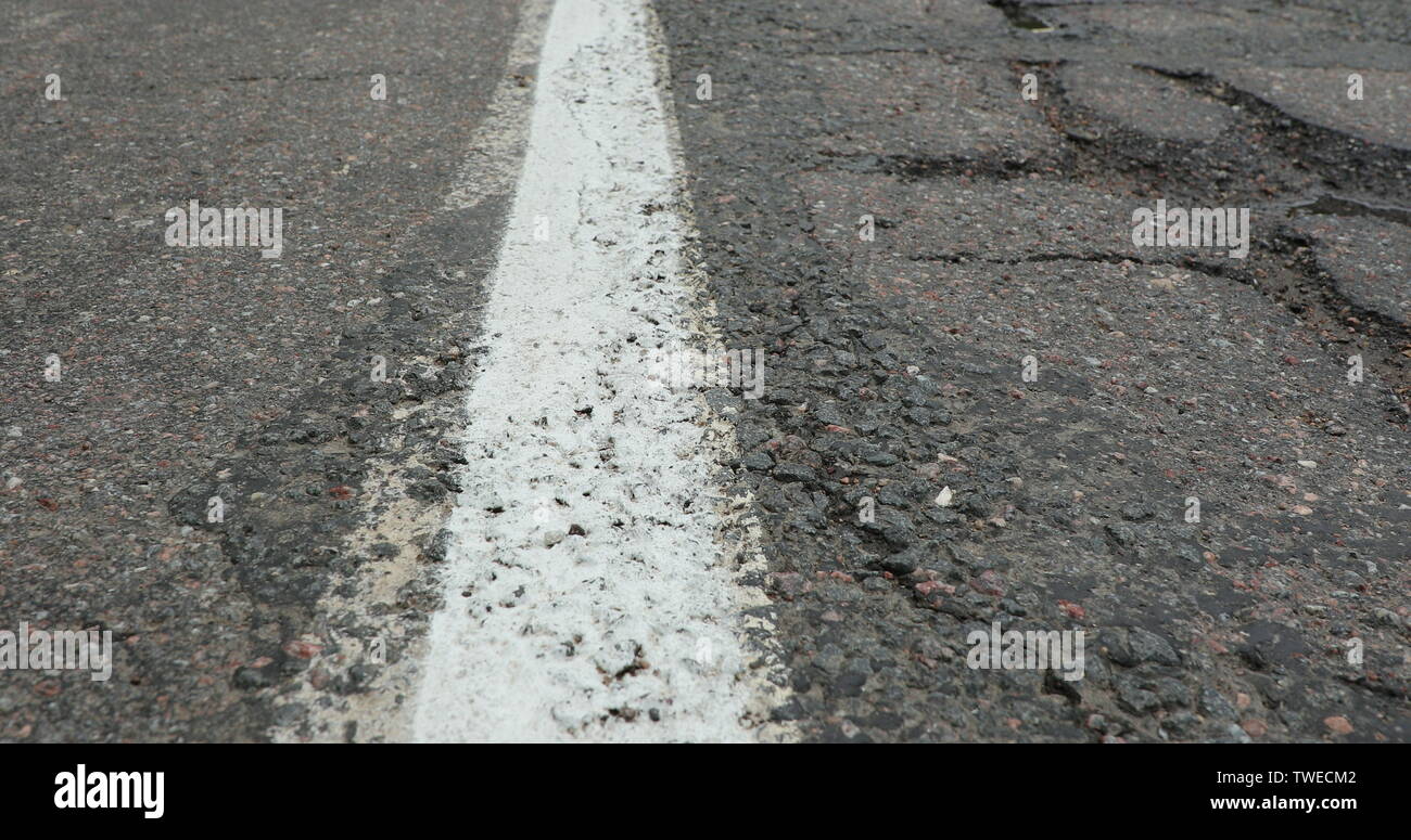 cracked and old asphalt with one solid white line Stock Photo