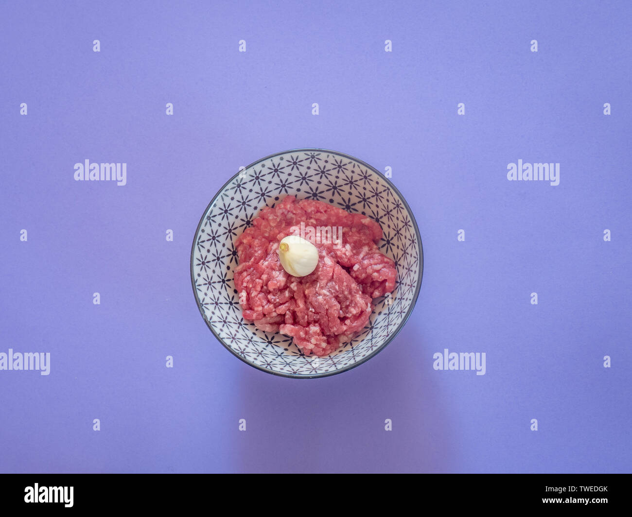 Minced beef meat in a bowl on purple background Stock Photo