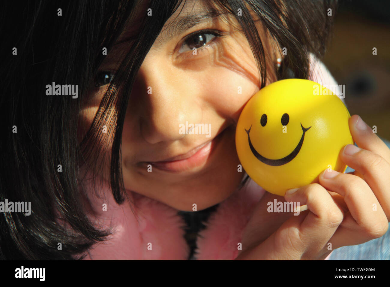 Portrait of a girl holding a ball with smiley face Stock Photo