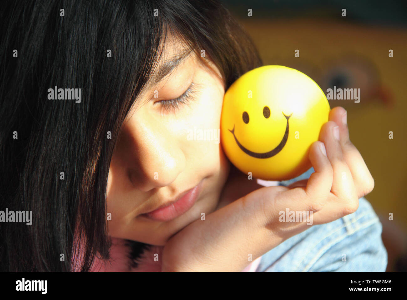 Close up of a girl holding a ball with smiley face Stock Photo