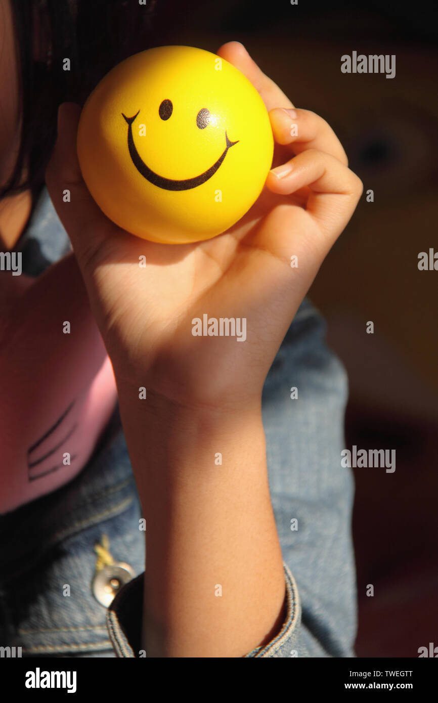 Girl showing a ball with smiley face Stock Photo