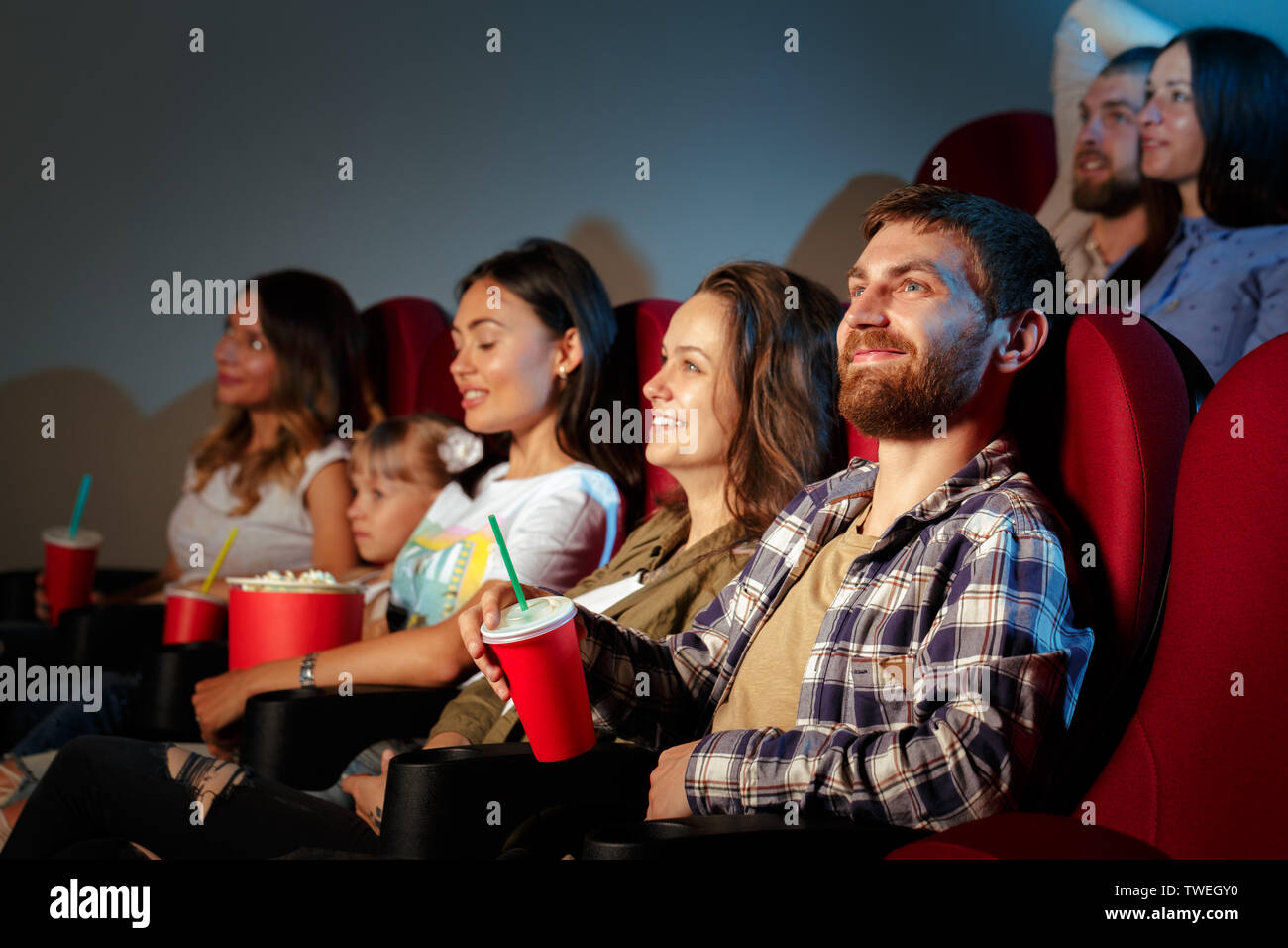 Group of friends sitting in movie theater with popcorn and drinks Stock ...