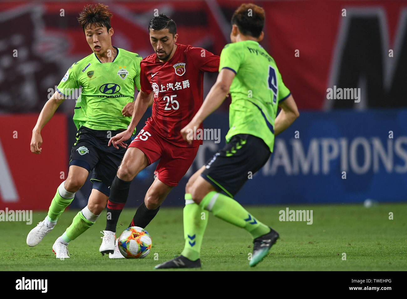 Uzbek football player Odil Ahmedov, center, of China's Shanghai SIPG F.C. passes the ball against players of South Korea's Jeonbuk Hyundai Motors FC in the eighth-final match during the 2019 AFC Champions League in Shanghai, China, 19 June 2019. Two-time champions Jeonbuk Hyundai Motors will take an advantage into the second leg of their 2019 AFC Champions League (ACL) Round of 16 game with Shanghai SIPG FC next week after netting an away goal in their 1-1 draw in Shanghai on Wednesday. Stock Photo