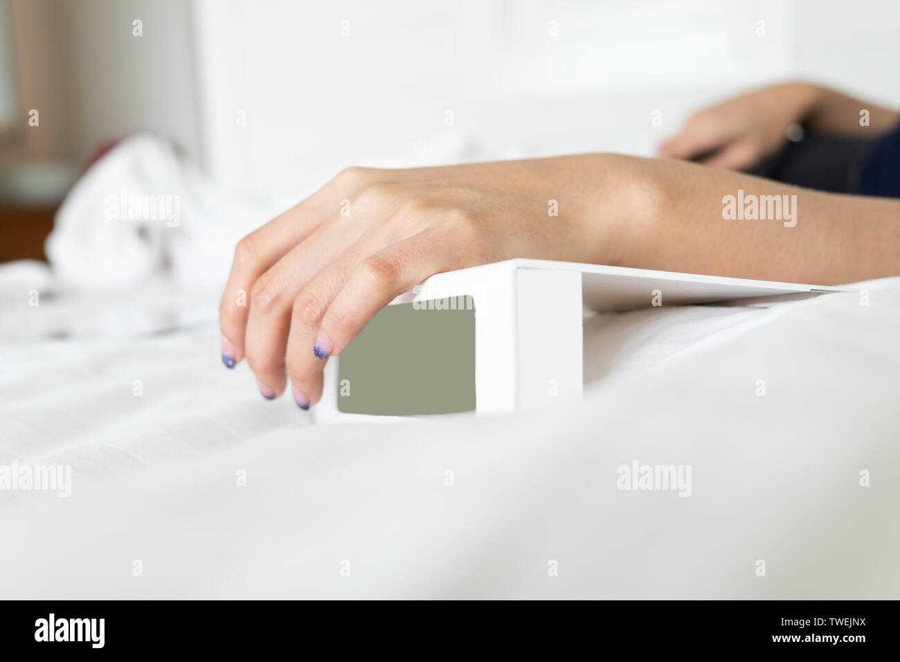 Woman Hand On White Digital Alarm Clock In Bedroom At