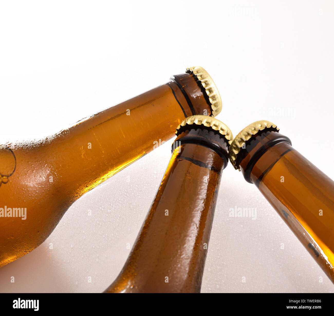 Three closed beer bottle necks on white table with fresh water drops Stock Photo