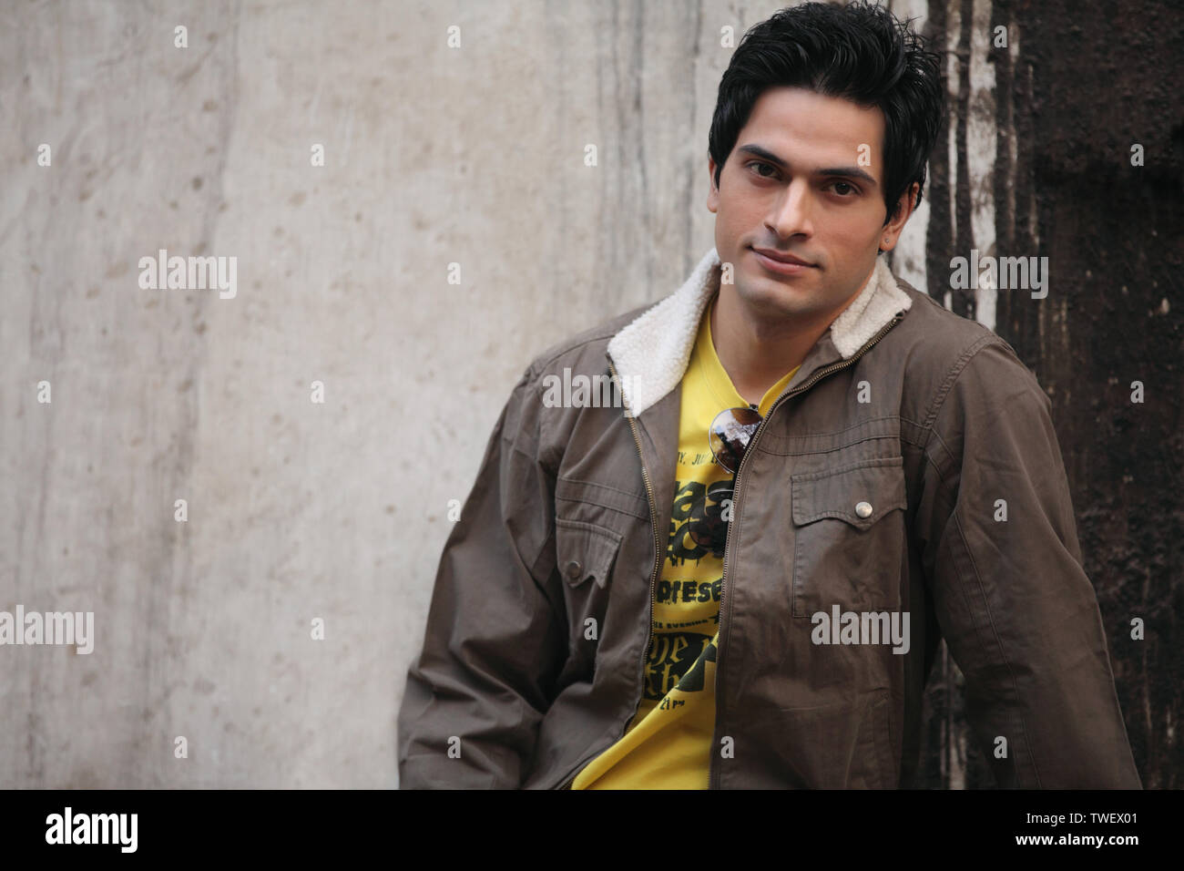Portrait of an Indian young man leaning against a wall Stock Photo - Alamy