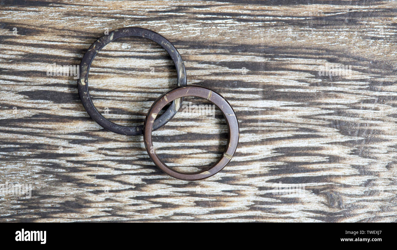 Pair of handmade coconut rings in wooden background. Natural and artisan wedding ring bands. Love and union concept. Stock Photo