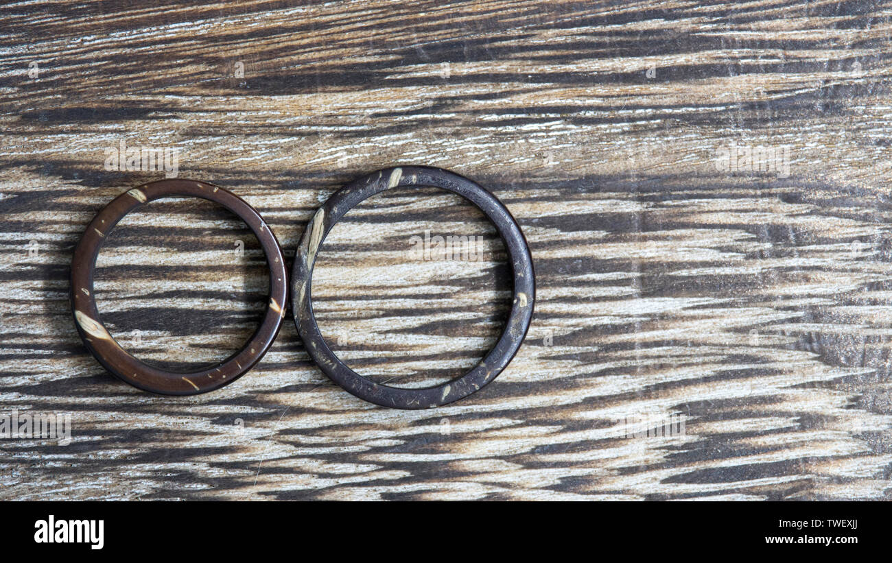 Handmade His and Hers coconut rings in wooden background. Unique, artisan wedding ring bands. Love and union concept. Stock Photo