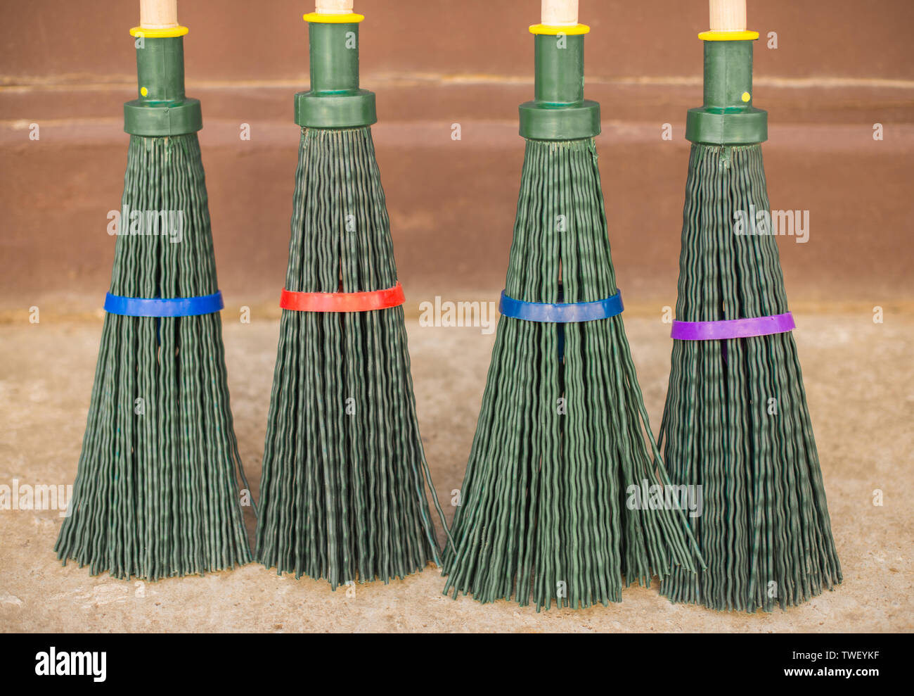 Four plastic garden broom against the wall. Stock Photo