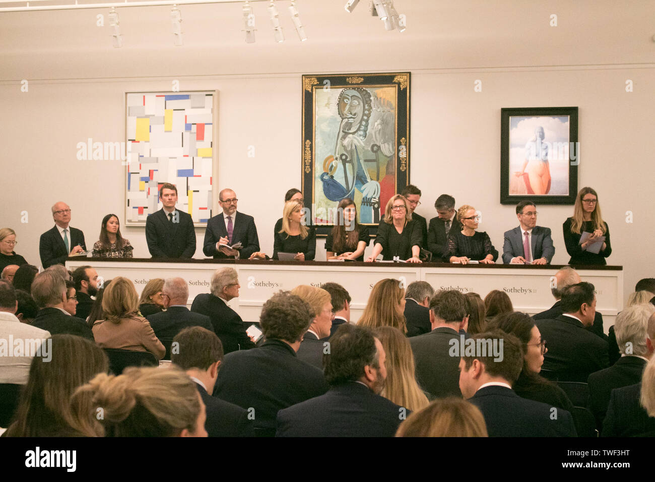 Sotheby's staff taking bids for  L-R 'Relational Painting No 60 by Fritz Glamer, oil on canvas, Estimate £450,000 which sold at hammer for £620,000;'Homme a la pipe by Pablo Picasso, Estimate £5,500,000m which sold at hammer for £6,500,000m; 'La magie noire, oil on canvas  by René Magritte, Estimate £2,500,000 which sold at hammer for £3,500,000 during the Impressionist & Modern Art Evening Auction  at Sotheby’s in London. Stock Photo