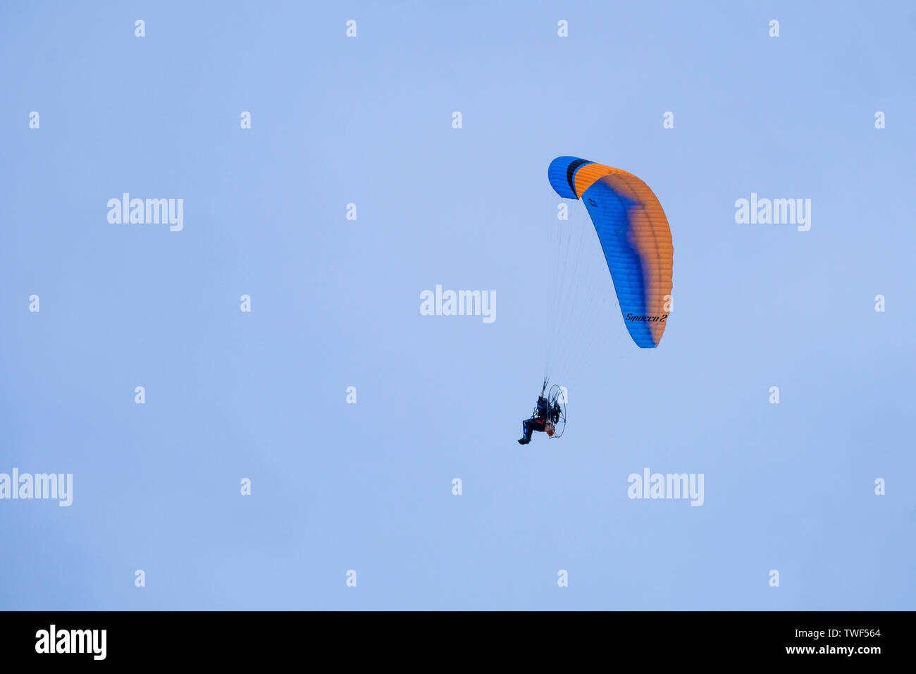 A motorised paraglider against a blue sky. Stock Photo
