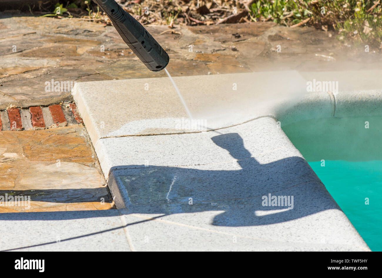 Border of a swimming pool border being cleaned with high pressure washer. Stock Photo