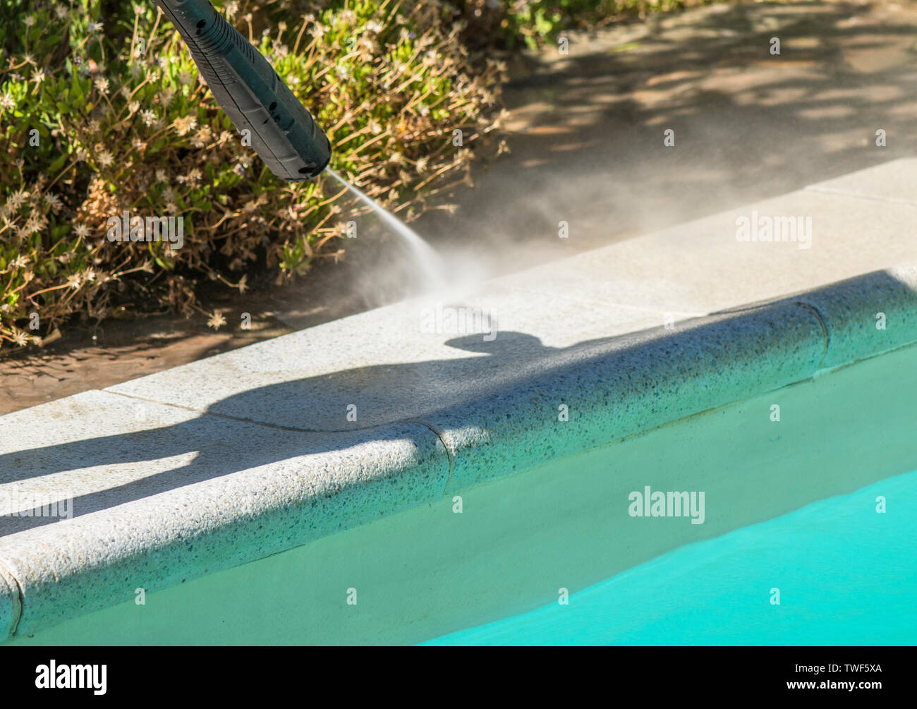 Border of a swimming pool border being cleaned with high pressure washer. Stock Photo